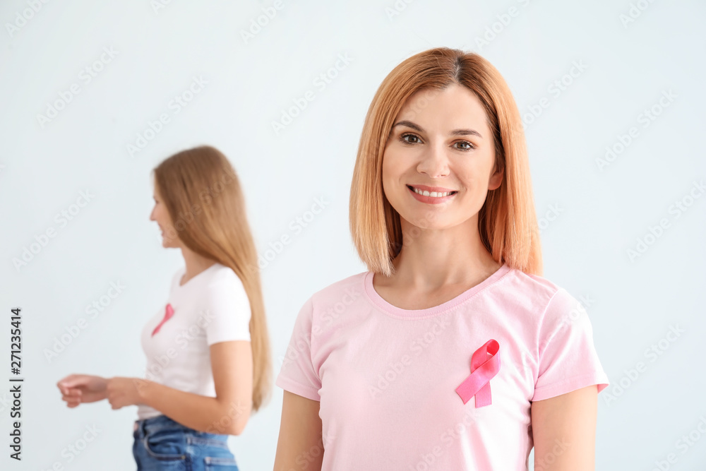 Beautiful woman with pink ribbon on light background. Breast cancer concept Beautiful woman with pink ribbon on light background. Breast cancer concept
