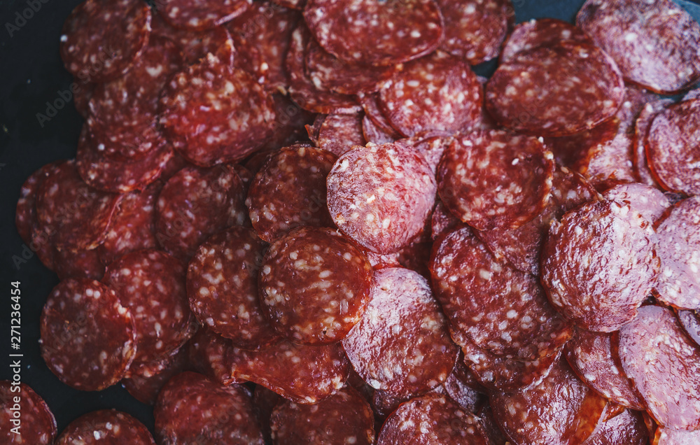 Thinly sliced sausage slices on a black stone board. Thinly sliced sausage slices on a black stone board.