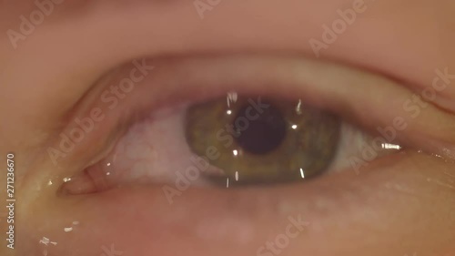 Close-up shoot of peson with green eye blinks fastly with tears falling being depressed and sad watching into camera.