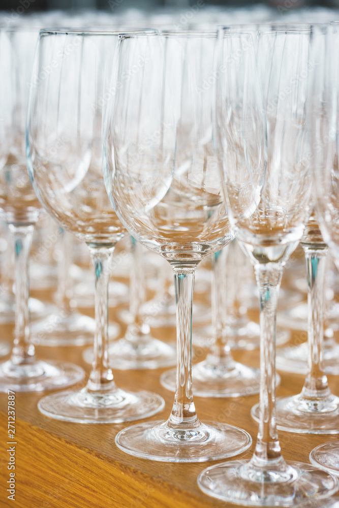 Several rows clear, clean glasses for wine and champagne on counter prepared for drinks. Several rows clear, clean glasses for wine and champagne on counter prepared for drinks.