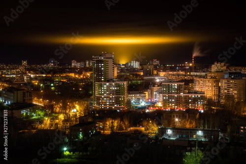 Night cityscape with yellow glow the glow from the industrial greenhouses in the sky