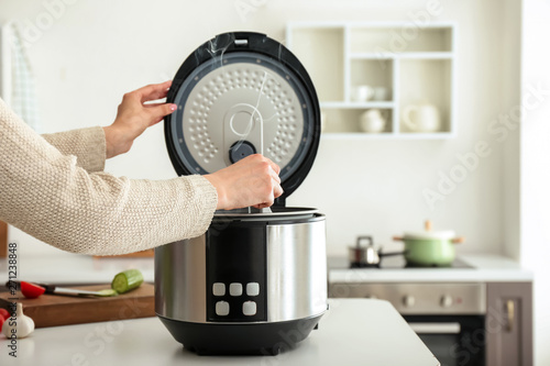 Woman cooking food in multi cooker at home photo