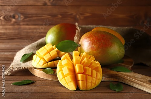 Fényképezés Board with tasty fresh mango on wooden table