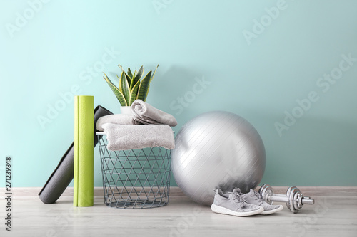 Set of sports equipment with fitness ball, towels and shoes near wall photo
