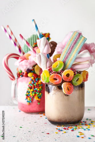 Different delicious freak shakes on light background