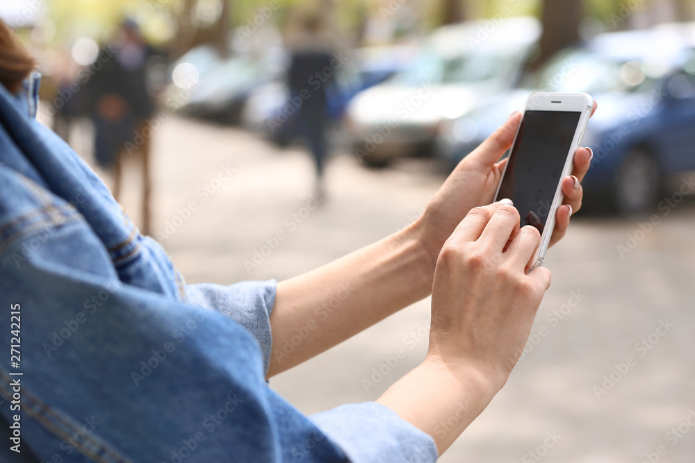 Young woman with mobile phone outdoors, closeup