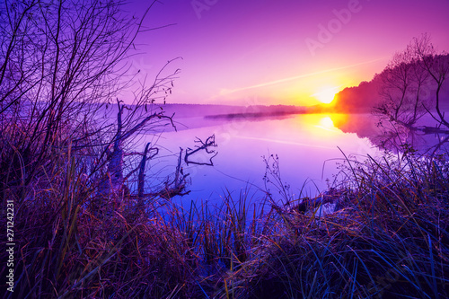 Magical purple sunrise over the lake. Misty morning. Rural landscape