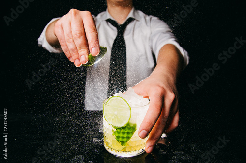 Professional bartender squeezing lime making Caipirinha cocktail