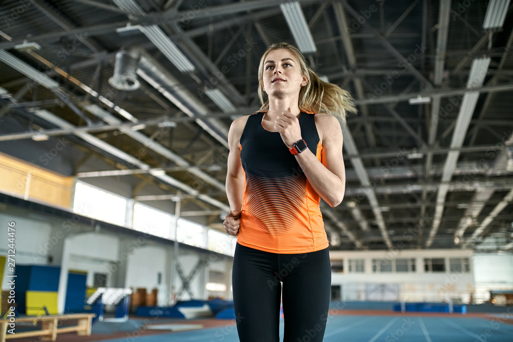 Athletic blonde woman training at indoor stadium Athletic blonde woman training at indoor stadium