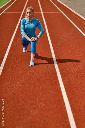 Sportive blonde woman training at open stadium