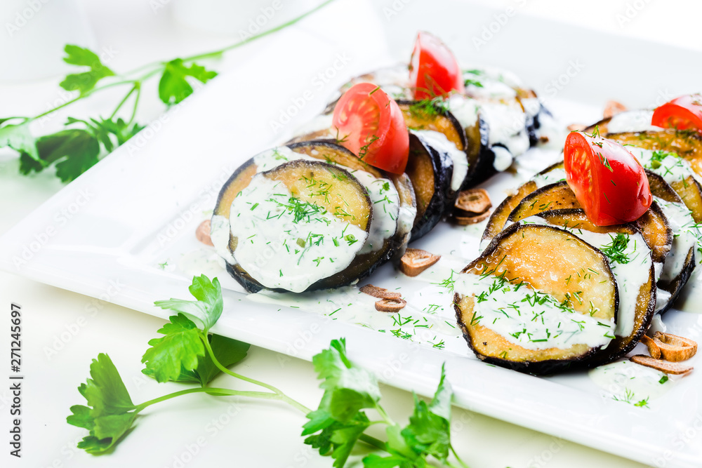 Grilled slices of eggplant and tomatoes in stack with spicy sauce
