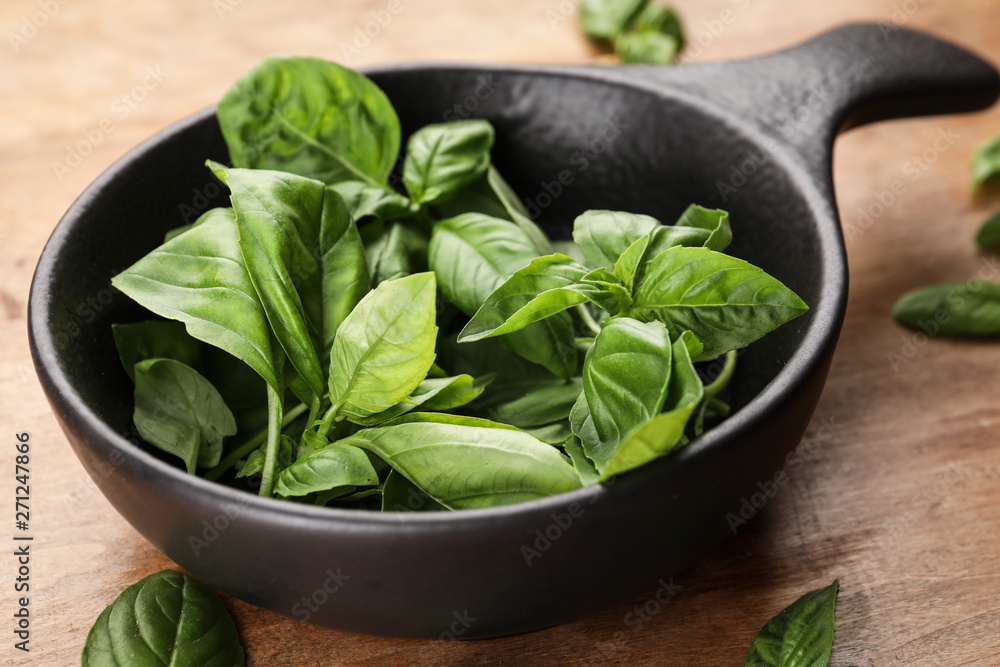 Frying pan with fresh basil leaves on wooden background Frying pan with fresh basil leaves on wooden background