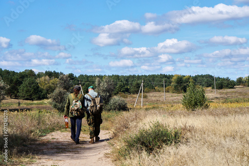 Two men are walking along the path to the forest