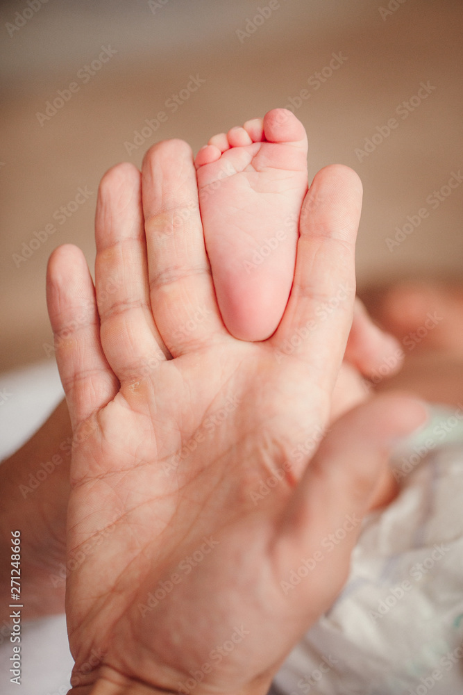 the mother's hand holds legs of a newborn baby
