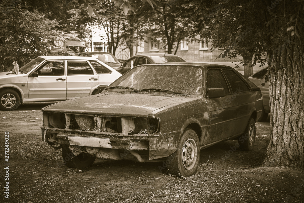 Damaged old production car in the city yard - retro style photo Damaged old production car in the city yard - retro style photo