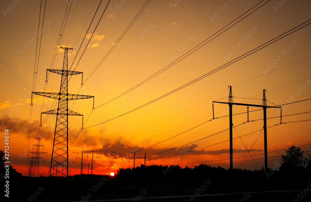 Fototapeta premium Silhouette High voltage electric towers at sunset time. High-voltage power lines. Electricity distribution station