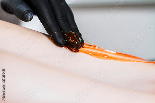 The procedure for removing hair with sugar paste - shugaring. The beautician applies sugar removal to the patient’s feet.