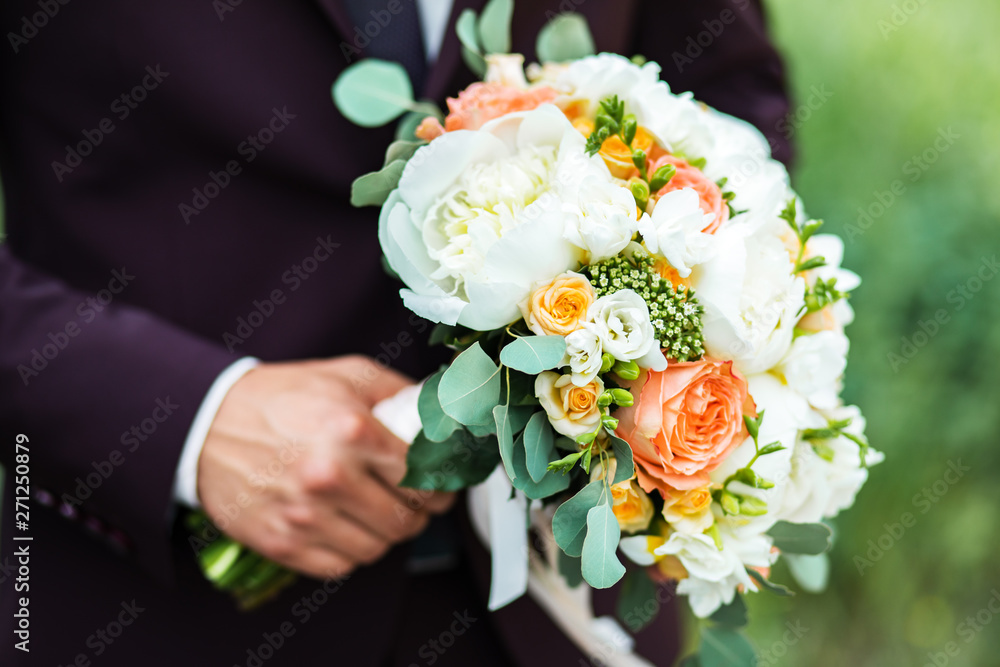 A beautiful bouquet of mixed flowers in the hand of the groom in a suit. Wedding bouquet of fresh flowers for the bride A beautiful bouquet of mixed flowers in the hand of the groom in a suit. Wedding bouquet of fresh flowers for the bride