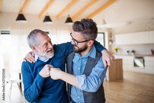An adult son and senior father indoors at home, making fist bump. Fototapet