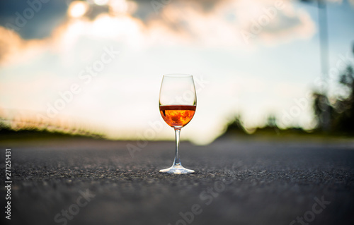 Red rose wine in glass with beautiful sunset reflection and cloudy sky