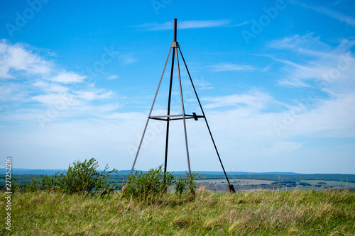 Metal tower on top of a hill. Geodesic, triangulation point. Summer landscape.