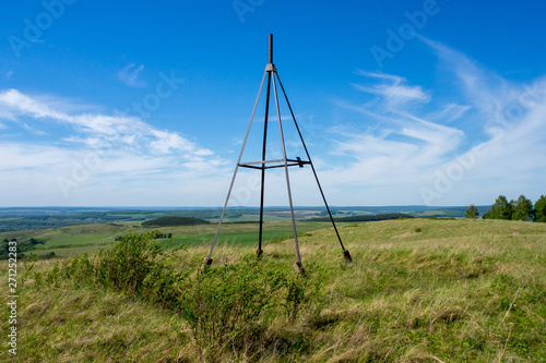 Metal tower on top of a hill. Geodesic, triangulation point. Beautiful summer landscape.