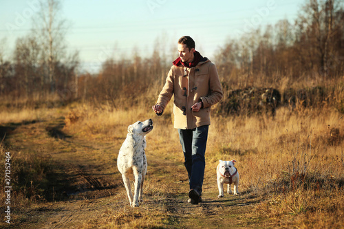Young happy european smiling and laughing walking in a field with two dogs