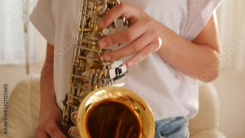 Teenager young girl at home practicing play sax musical composition closeup