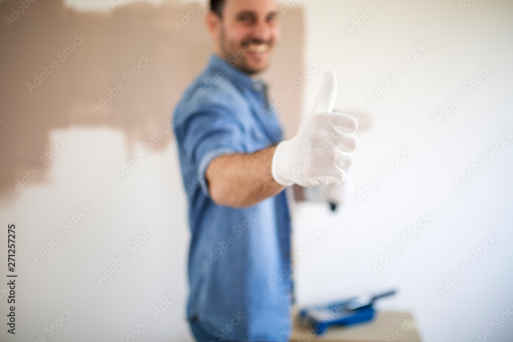 Handsome man painting walls in his apartment.