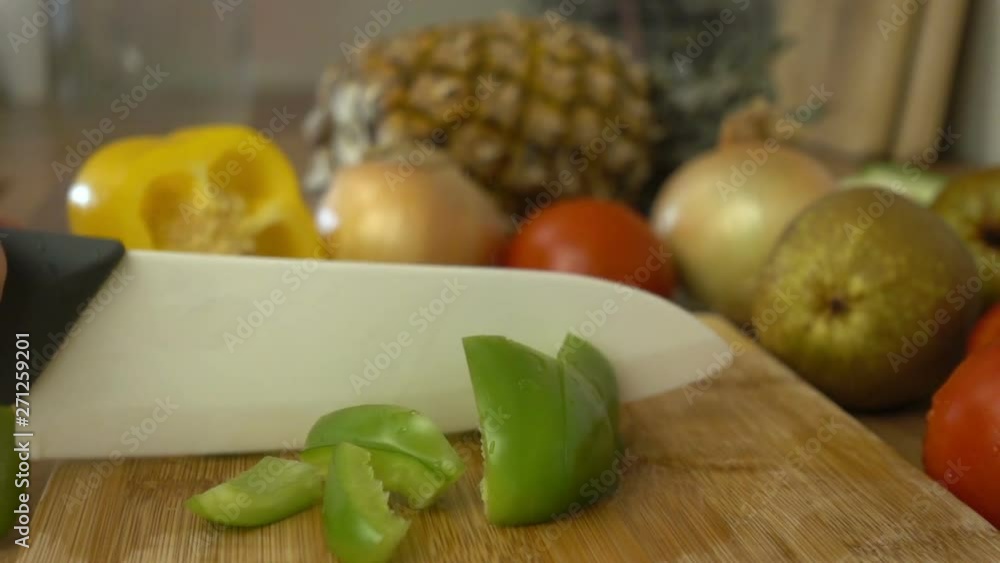 Chopping green paprika on the wooden cutting board in slow motion. Chopping green paprika on the wooden cutting board in slow motion.