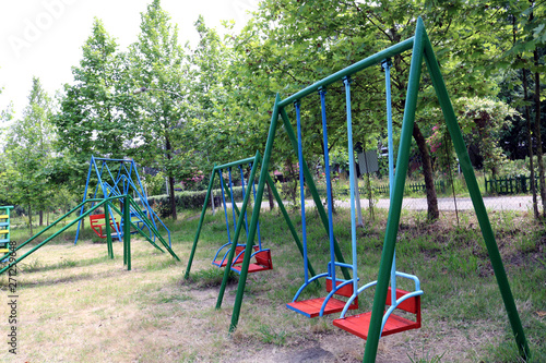 Swings in the garden. Children's playground among greenery