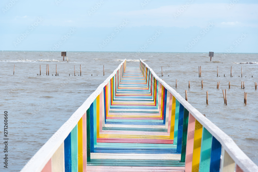 colorful rainbow wood bridge into the sea with blue sky background colorful rainbow wood bridge into the sea with blue sky background