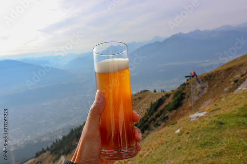 Beer on mountain view. Hand holding photo