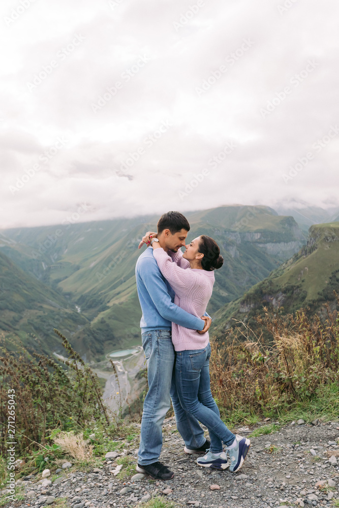 beautiful couple woman and man hugging against the background of the mountains