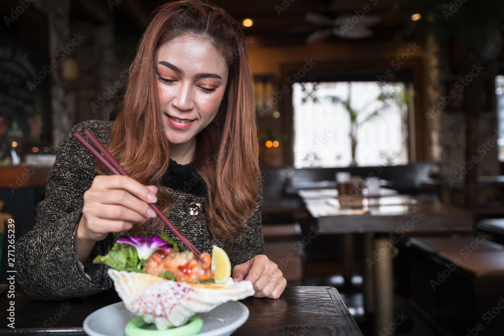 woman eating salmon sashimi spicy salad in restaurant