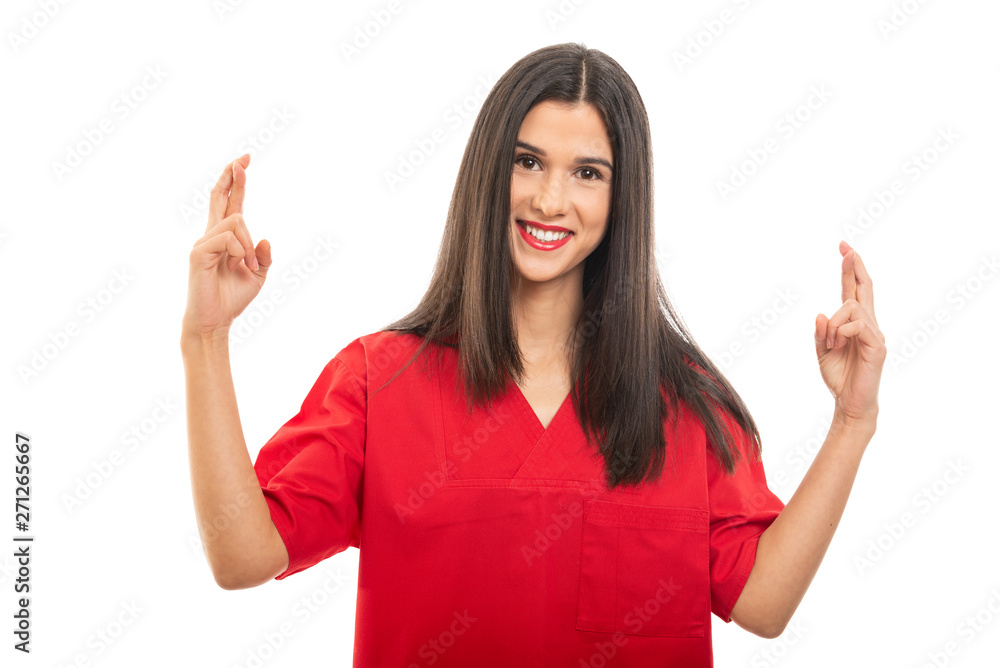 Portrait of beautiful nurse wearing red scrubs making fingers crossed gesture Portrait of beautiful nurse wearing red scrubs making fingers crossed gesture