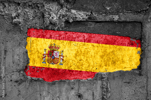 The flag of Spain on a dirty wooden surface, built into a concrete base, with scuffs and scratches. Loss or destruction conception.