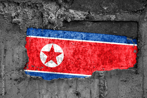 The flag of North Korea on a dirty wooden surface, built into a concrete base, with scuffs and scratches. Loss or destruction conception.