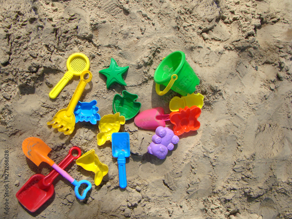 Multi-colored toys on the sand. Sunny day at the beach Multi-colored toys on the sand. Sunny day at the beach