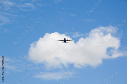 plane flying in the sky over some clouds in a sunny day