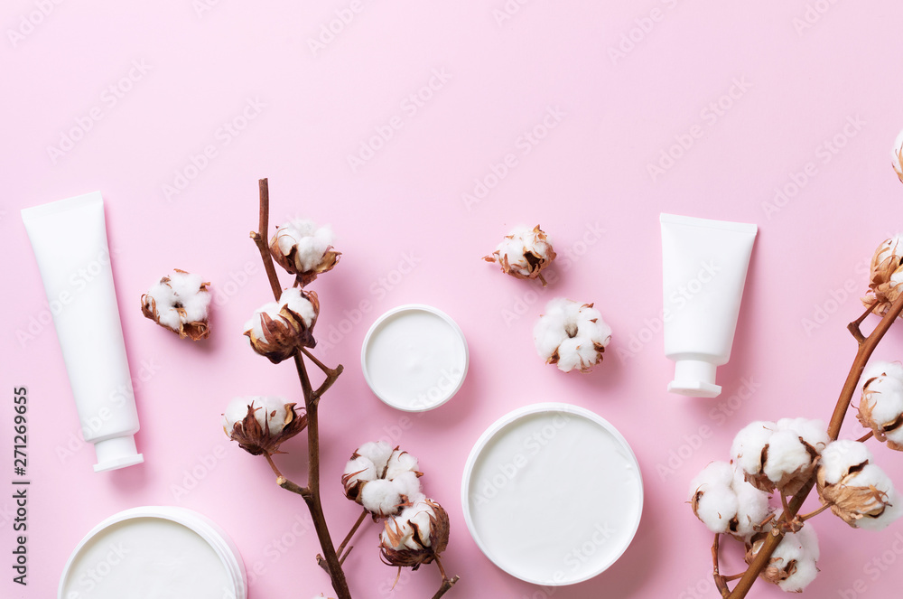 Fluffy cotton flowers, face cream, body butter on pink background with copy space. Cosmetics, beauty, spa concept. Top view. Flat lay Fluffy cotton flowers, face cream, body butter on pink background with copy space. Cosmetics, beauty, spa concept. Top view. Flat lay