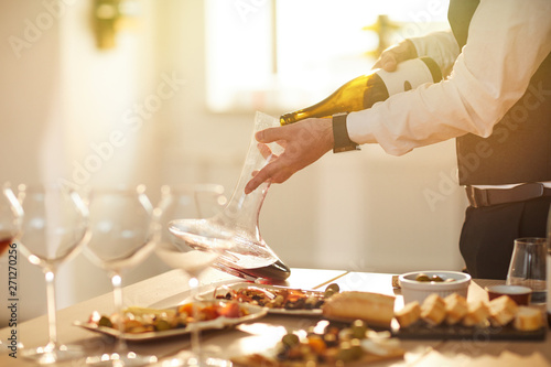 Mid section portrait of professional sommelier pouring wine while preparing for wine tasting session in sunlight, copy space photo