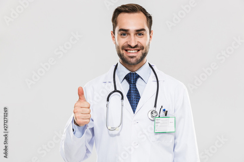 Portrait of happy young medical doctor with stethoscope smiling at camera and showing thumb up
