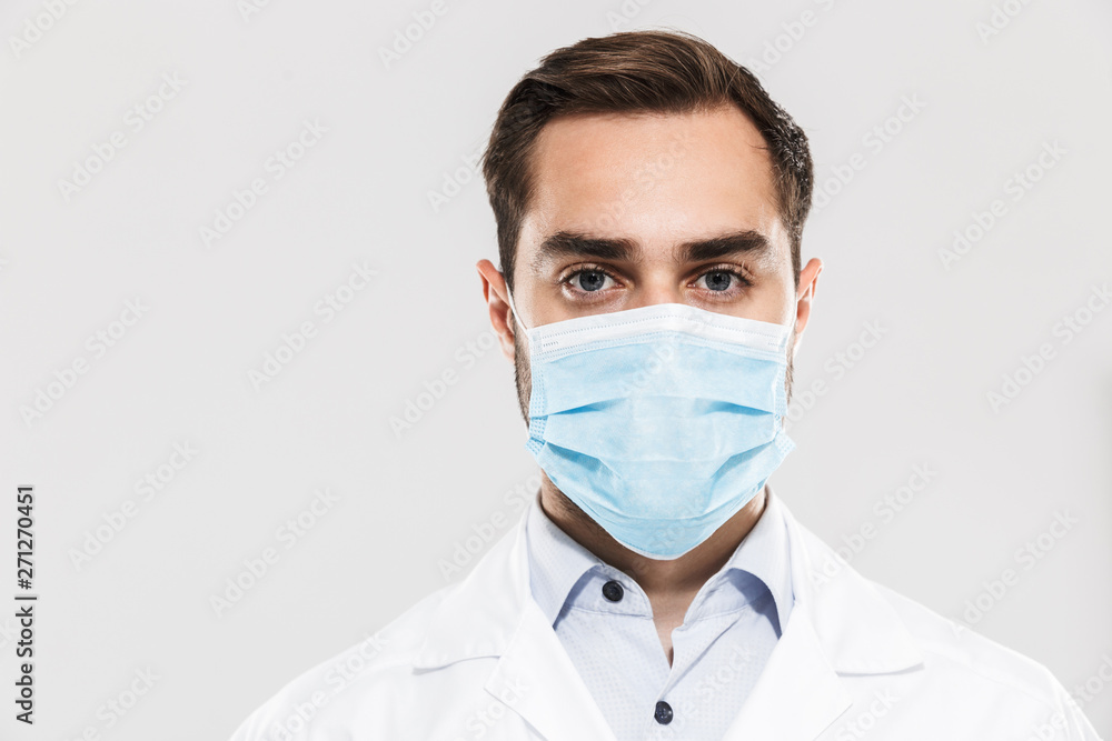 Portrait of european young medical doctor wearing sterile mask working in clinic laboratory and looking at camera