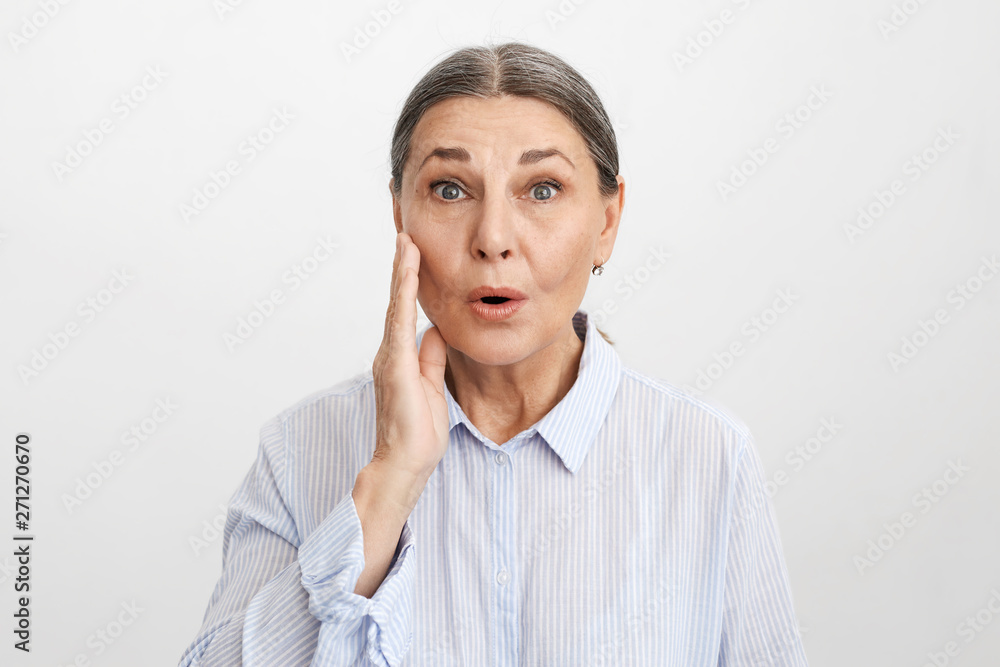 Isolated image of shocked mature businesswoman keeping mouth opened and touching face, having forgetful frustrated look because she forgot about important business meeting. Human emotions and feelings Isolated image of shocked mature businesswoman keeping mouth opened and touching face, having forgetful frustrated look because she forgot about important business meeting. Human emotions and feelings