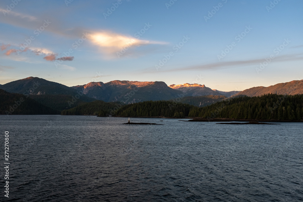 The view at sunset from the side of a ferry as it makes its way through the Inside Passage off the rugged west coast of Canada, the light fading behind the hills in the distance, nobody in the image