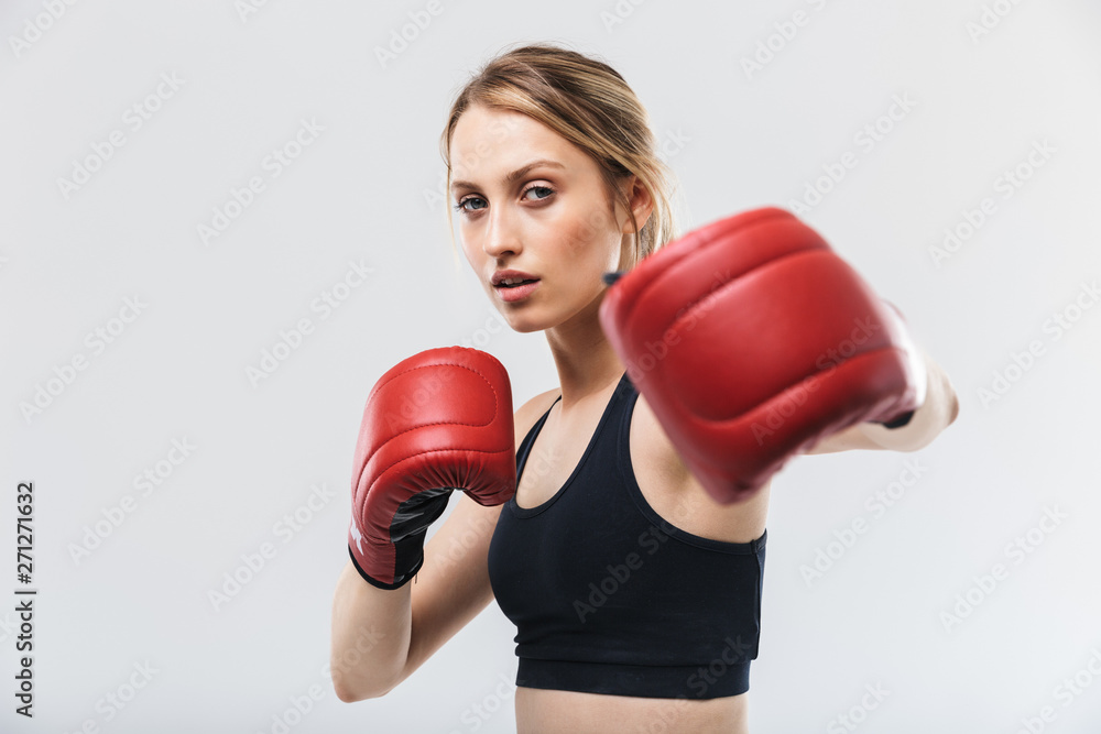 Image of athletic blond woman 20s dressed in sportswear and boxing gloves working out and during fitness in gym