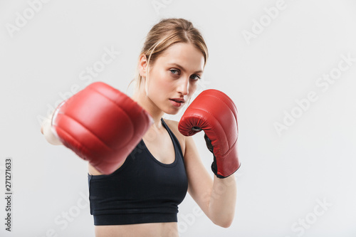 Image of healthy blond woman 20s dressed in sportswear and boxing gloves working out and during fitness in gym