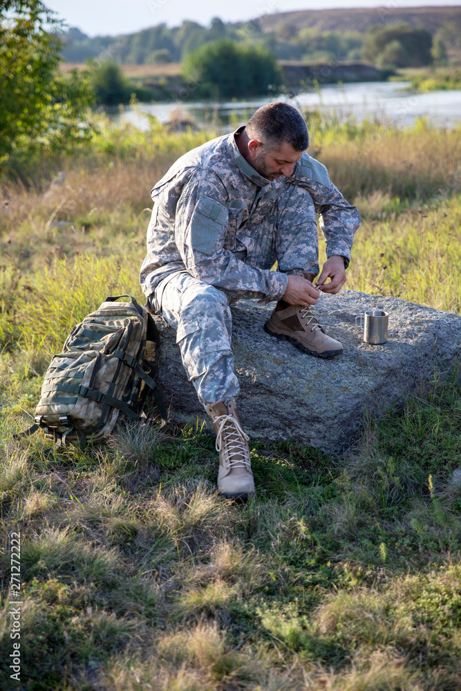 Soldier tying shoes. Soldier. Soldier in gear. The soldier sits and rests.