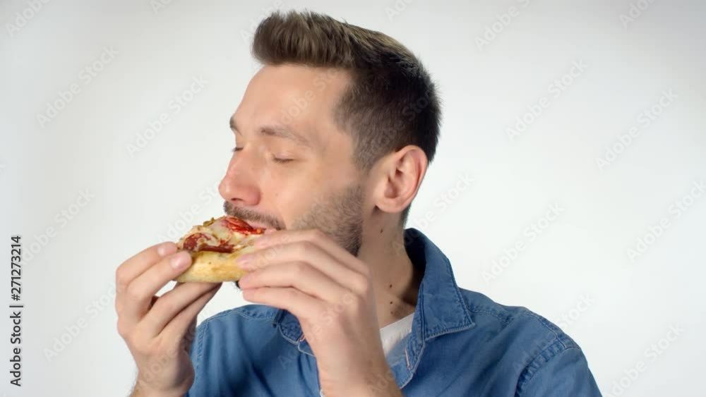 Portrait of man with beard standing isolated on white background and taking bite out of pizza slice, then chewing and looking at camera Portrait of man with beard standing isolated on white background and taking bite out of pizza slice, then chewing and looking at camera